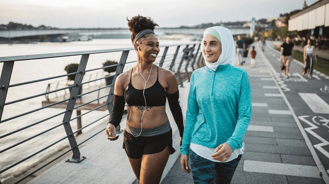 Two women brisk walking along a waterfront path