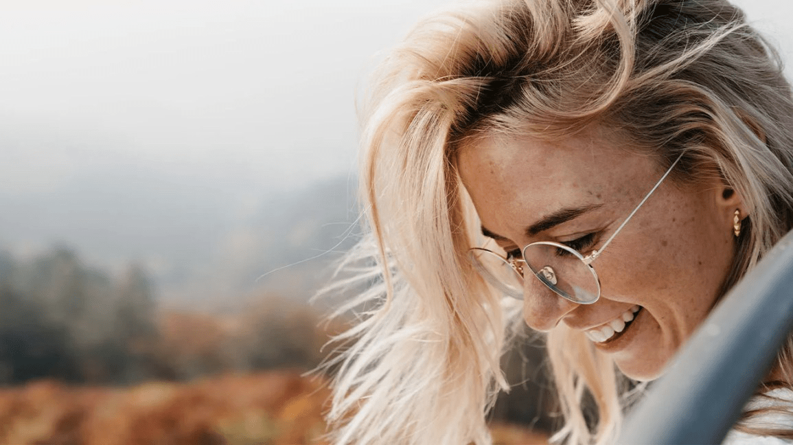 Женщина в очках улыбается на улице Женщина в очках улыбается на улице