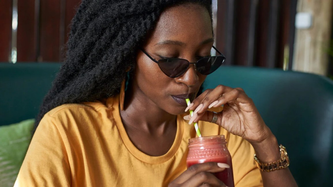 Человек на диване пьет смузи из стакана