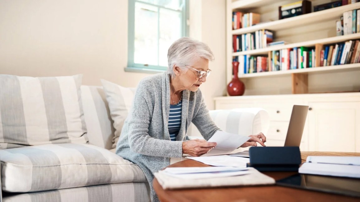 Older woman compiling documents on her living room couch
