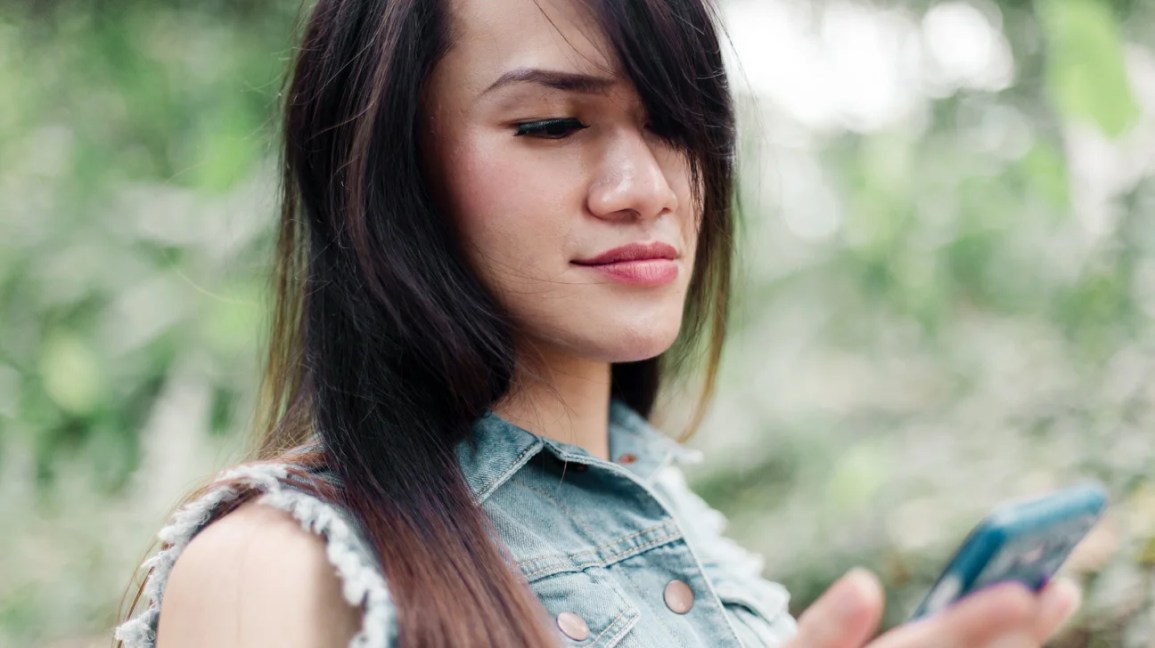 Портрет трансфемининного человека с длинными каштановыми волосами и макияжем