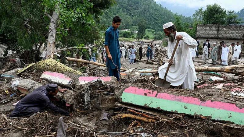 Getty Images A man in white robes and hat shovels among debris, alongside a young boy in blue robes and another man in darker robes down on all fours and digging in the mud