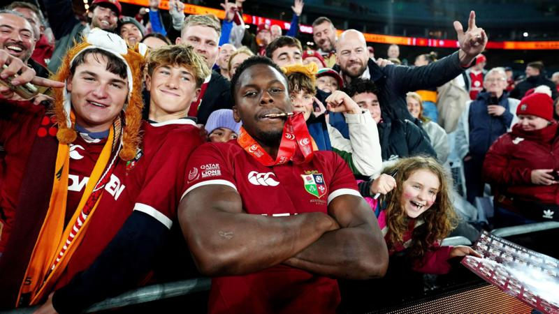Maro Itoje, with his winners medal in his mouth, poses for a picture with fans