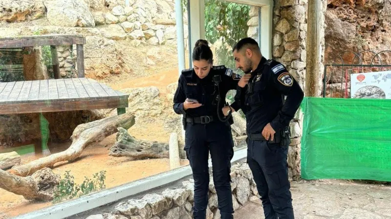 Israel Police Two police officers stand next to thick glass by the enclosure