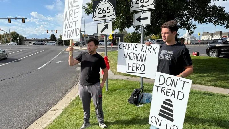 INLIBER / Christal Hayes McKinley Shinkle (left) and his cousin, Anthony, hold signs in support of Charlie Kirk near the entrance of the Utah Valley campus 