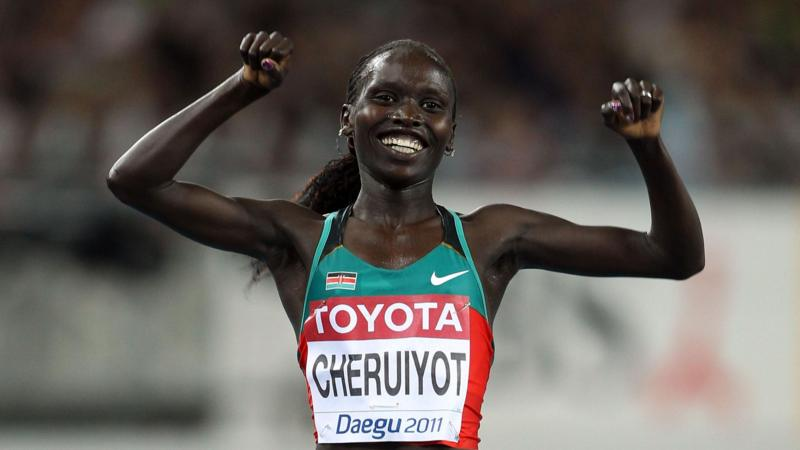Vivian Cheruiyot holds her arms aloft in celebration and smiles while wearing a green and red Kenyan running top which bears her surname and Daegu 2011 on the front