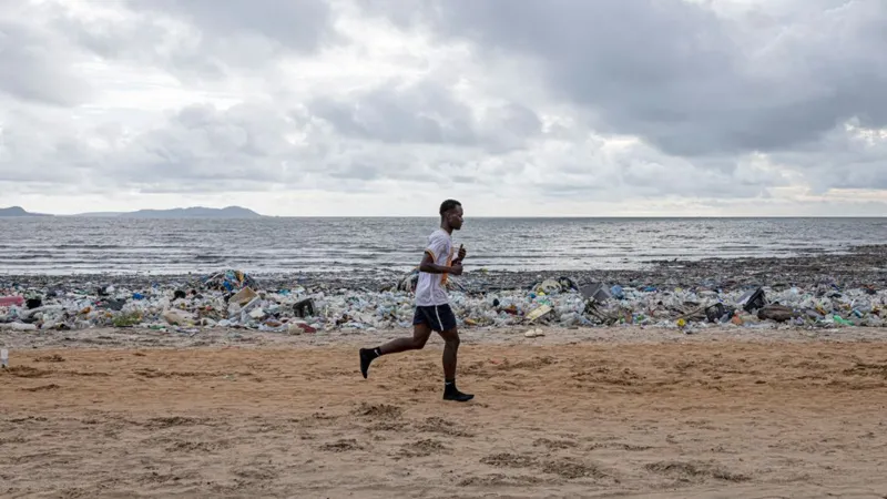 A runner jogs along a beach strewn with plastic waste in Conakry, Guinea, 30 August 2025