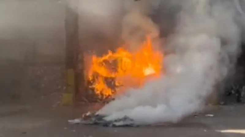 Biffa A fire rages in a recycling facility. Plumes of smoke rise in the foreground, in front of a pile of material burning with bright orange flames.