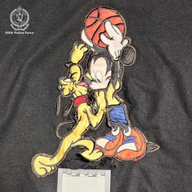 NSW Police A black Mickey Mouse T-shirt with a hole in the middle and an evidence card placed on it