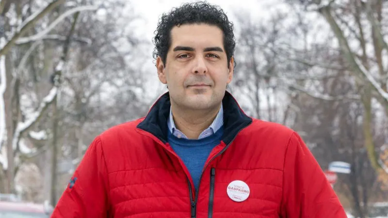 Getty Images Vince Gasparro, he is looking at the camera, he has black hair and is wearing a blue jumper and shirt with a red jacket.