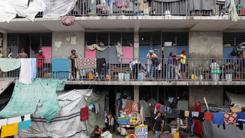 Reuters A school that is being used as a shelter, with people standing on balconies, washing hanging out and makeshift shelters made from tarpaulins, in Port-au-Prince, October 2025