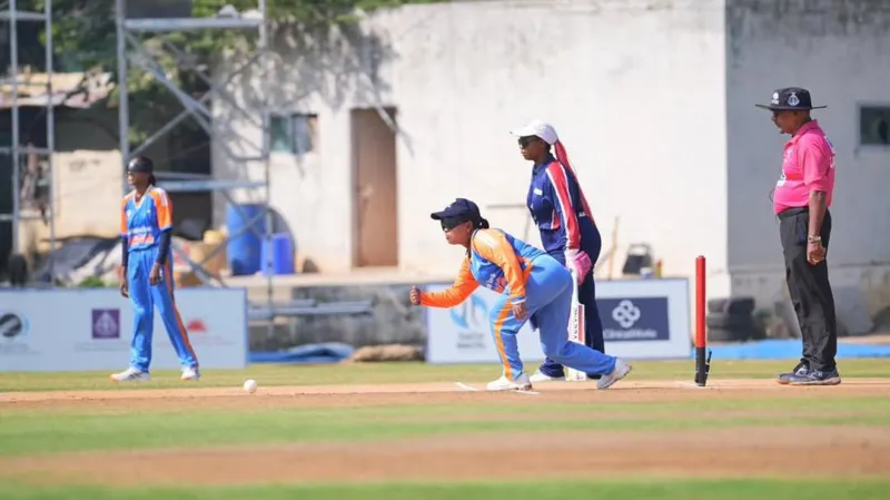 Cricket Association for the Blind in India The image from the tournament shows a player bowling, surrounded by teammates and an umpire wearing a pink jersey.