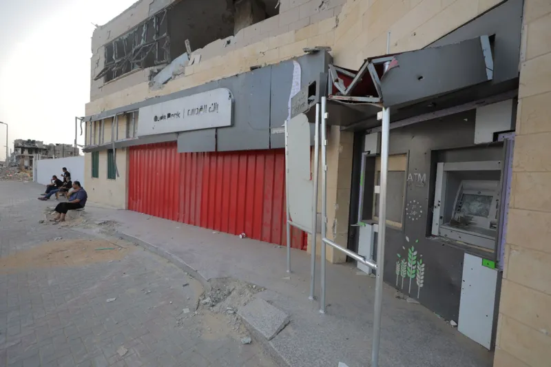 Anadolu via Getty Images A man passes by a closed bank branch as the cash crisis worsens in Deir al Balah, Gaza on May 26, 2024. Many bank buildings in the Gaza Strip have been destroyed as a result of Israeli attacks