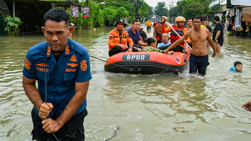 Getty Images A rescue worker pulls a dinghy containing evacuees along a flooded road in northern Sumatra