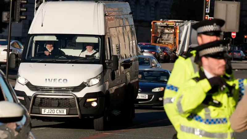 PA Media A white Iveco van on a road with uniformed police officers stood in the foreground