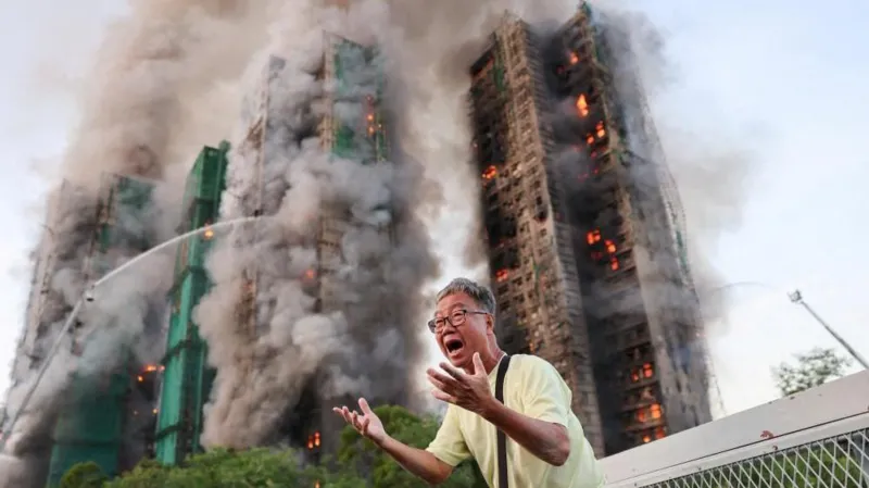 Reuters A man gestures in distress as the tower blocks burn behind him.