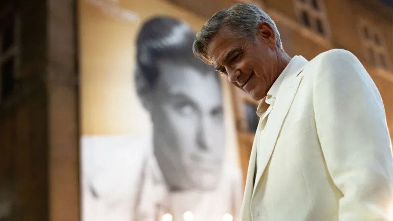 Netflix George Clooney in Jay Kelly, wearing a white suit and smiling at the gound