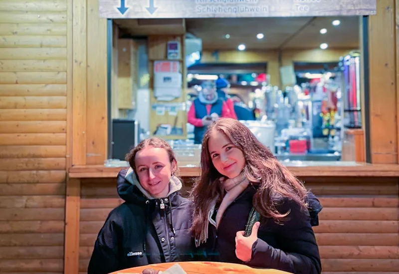 Two young women enjoy chocolate-covered strawberries at a Berlin Christmas market