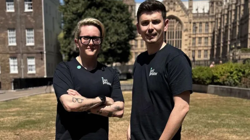 Kate Margolis Kate Margolis with a business partner standing outside the Houses of Parliament on a sunny day. They are both wearing black T-shirts with the words 'Pet proov' on them in white writing