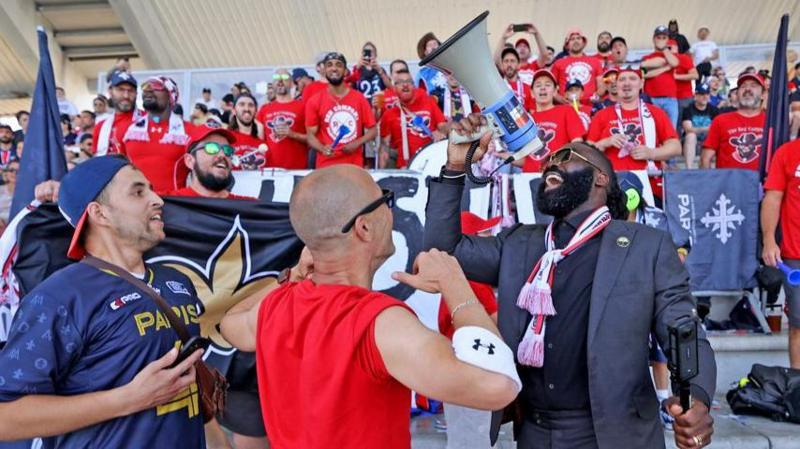 Demario Davis shouts into a megaphone surrounded by fans at a Paris Musketeers game