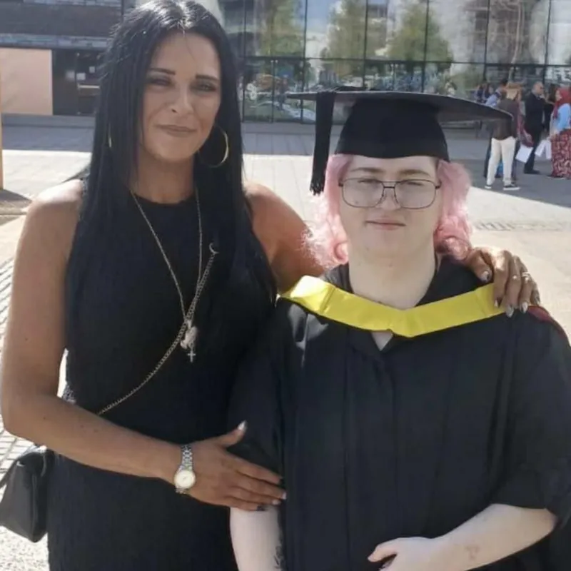 Лианна Ханнам улыбается на фоне стеклянного здания с дочерью в темном наряде