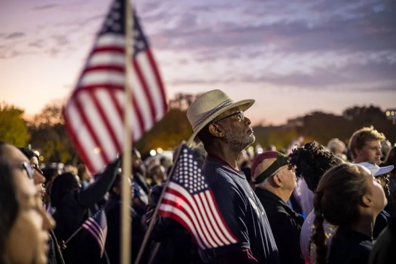 Getty Images People in crowd carrying USA flags as they watch Kamala Harris speak