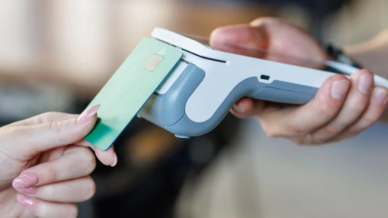 Getty Images A woman taps her green credit card on a wireless payment terminal 