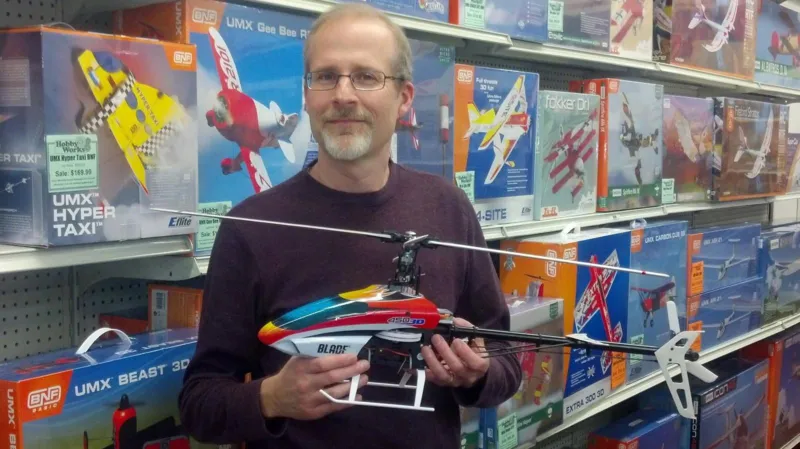Michael Brey Michael Brey poses inside a toy store, holding a toy helicopter, with boxes of toy planes seen on the shelves behind him