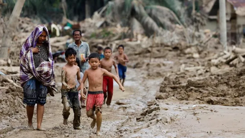 Reuters: people walk along a muddy road left by flooding