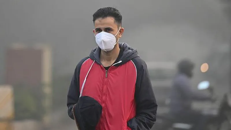 Getty Images A man wearing a pollution mask and a red-and-black wind cheater among commuters seen moving through dense smog on a cold morning near MDI Institute in Delhi suburb Gurugram on 14 December