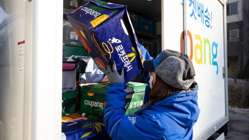 Getty Images A Coupang employee wearing a protective mask unloads an eco-bag carrying fresh food from a delivery truck in Bucheon