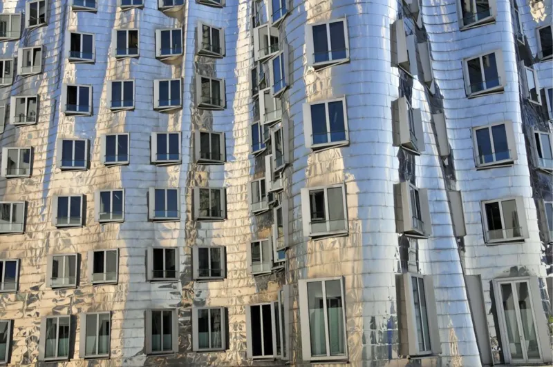 JOKER/Walter G. Allgöwer/ullstein bild via Getty Images Der Neue Zollhof building in Düsseldorf, Germany - the photograph is a close-up of the buildings stainless-steel facade lined with windows of varying sizes