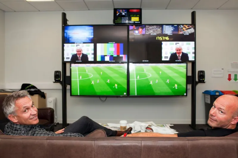 Gary Lineker and pundits watching football on screens at a studio