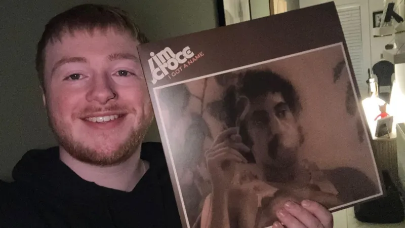 Saul with vinyl records against a green wall.