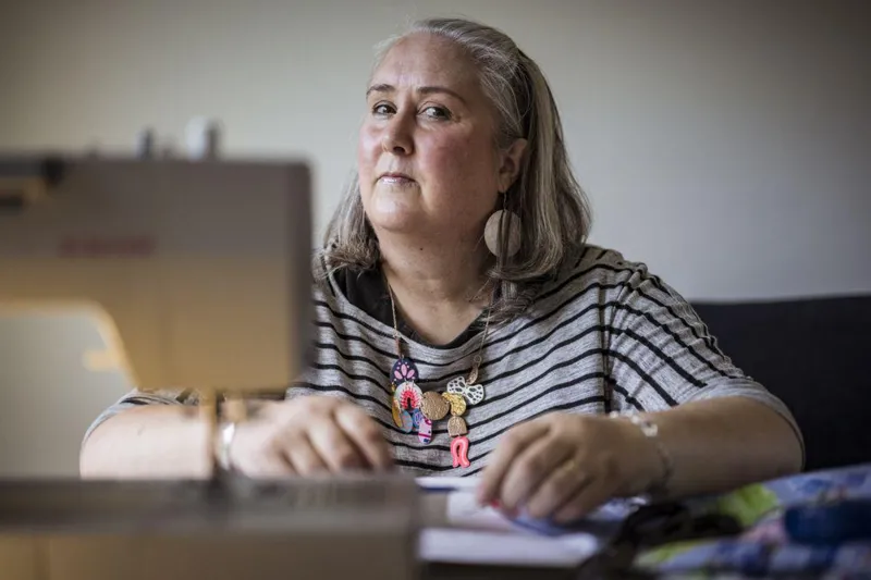 Tanaffusga chiqqan mato namunasi ustida ishlayotgan ayol; turli rangli matolar yonida yotadi