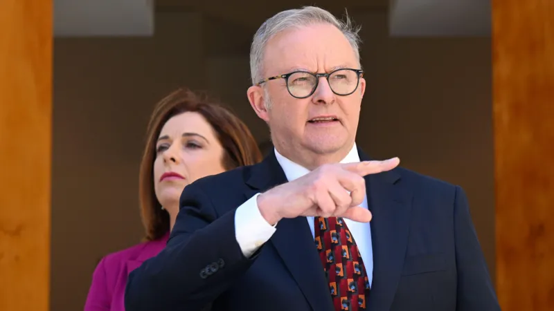 EPA A man in a suit and round glasses puts off camera, as a woman in a pink suit jacket looms behind him
