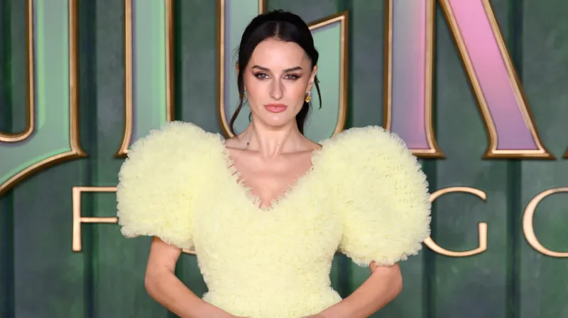 Amber Davies sariq rangli kiyingan, Wicked yozuvi yonida suratga olingan